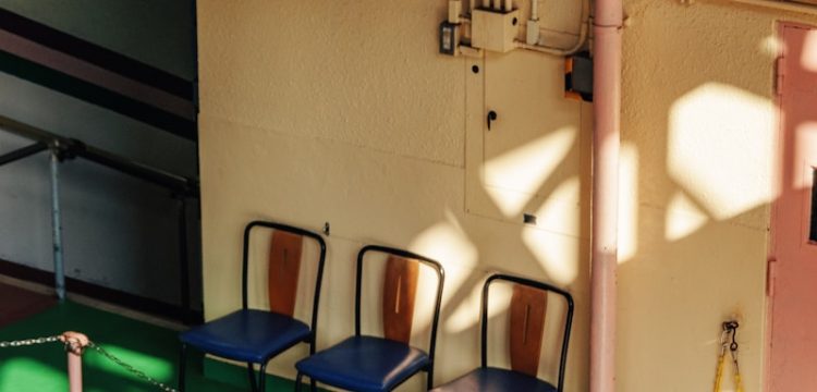 Three chairs lined up in a hallway with sunlight.