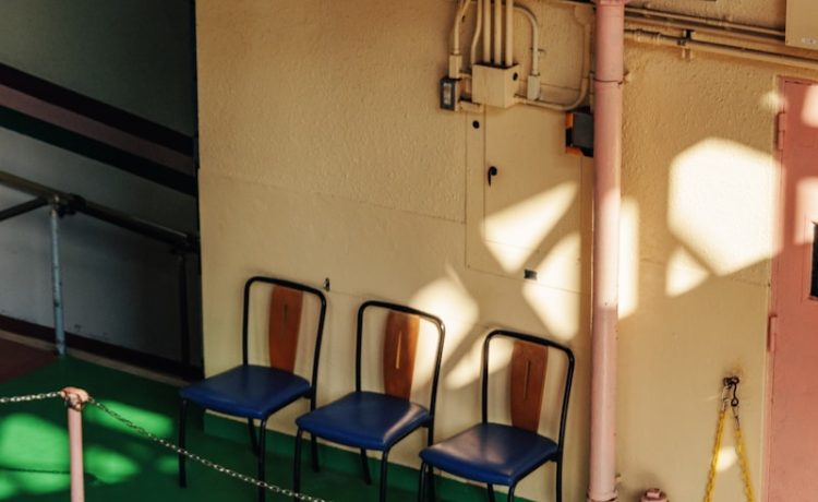 Three chairs lined up in a hallway with sunlight.