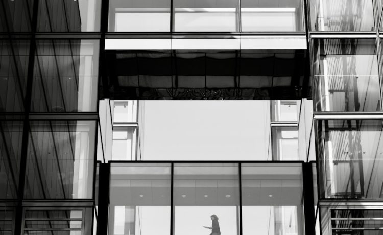 Woman walking through modern office building windows