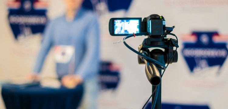 a person standing behind a microphone with a cell phone on a tripod